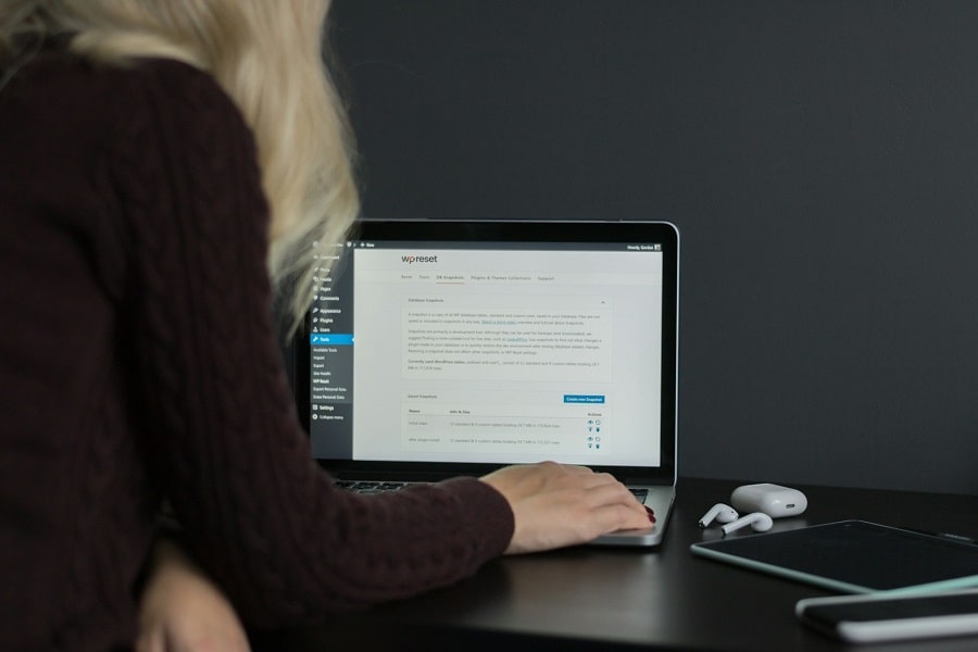 Woman in black sweater about to reset her WordPress site with a free plugin