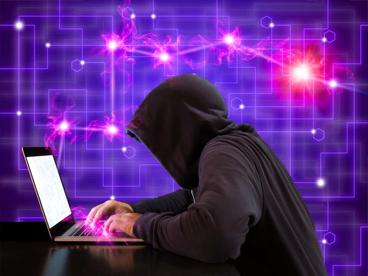 Hacker in hoodie using a laptop