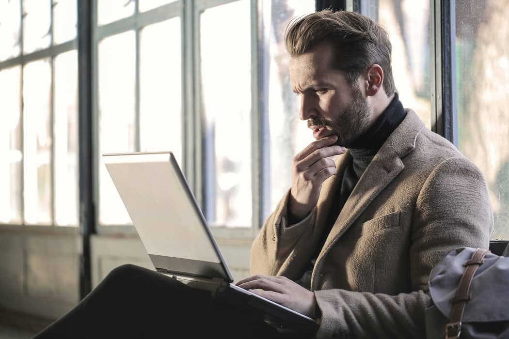 Man holding his chin facing laptop computer